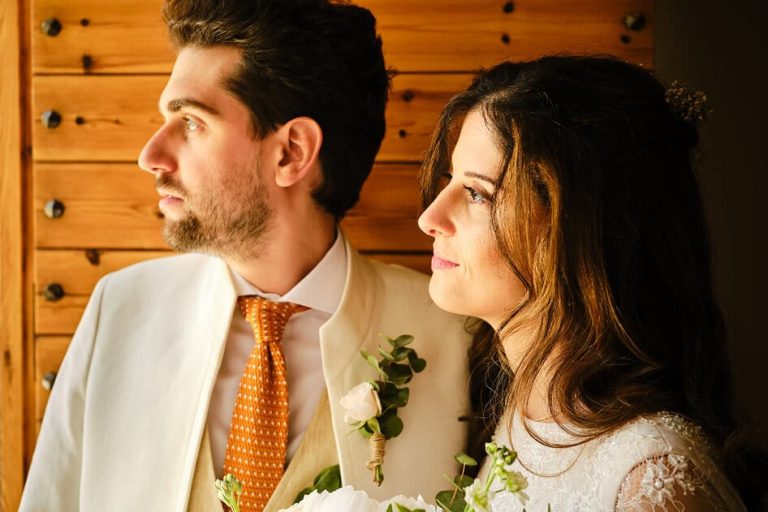 Pareja de novio y novia en el día de su boda mirando a través de una ventana